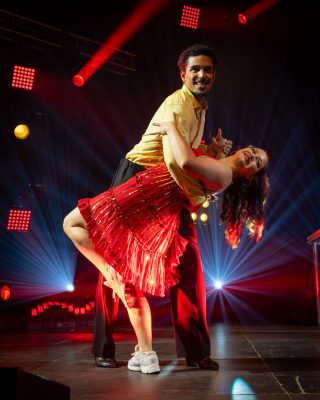 Couple de danseurs de salsa sur scène sous une lumière rouge