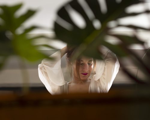 Portrait vu à travers une boule de verre, entre des feuilles de monstera