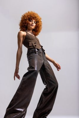 Femme aux cheveux roux bouclés en tenue marron, photo studio