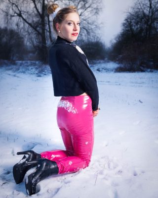 Femme en pantalon rose agenouillée dans la neige