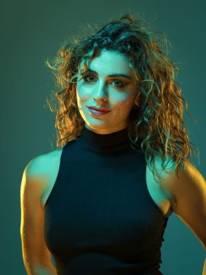 Portrait d'une femme aux cheveux bouclés sous une lumière turquoise