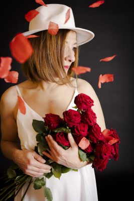 Femme au chapeau blanc tenant un bouquet de roses rouges