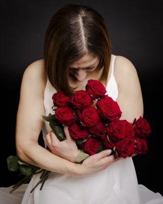 Femme respirant un bouquet de roses rouges