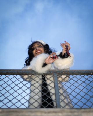 Femme souriante accoudée à une rambarde sous un ciel bleu, Paris