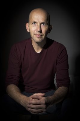 Portrait studio d'un homme en pull bordeaux sur fond noir