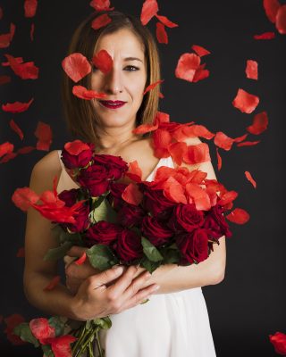 Femme tenant un bouquet de roses rouges sous une pluie de pétales